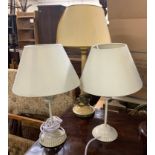 A pair of white painted metal bedside lamps; together with one other painted metal column lamp,