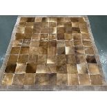 A patchwork cowhide rug with suede edging, 196cm square