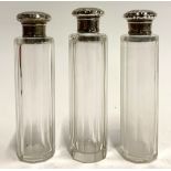 Three cut glass dressing table bottles with silver lids, the lids with hammered design and
