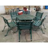 A bespoke green painted wrought iron hexagonal garden table with undershelf and parasol hole, 115cmW