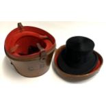 A very large silk top hat, size 7 1/2, in a leather hat box with red velvet interior