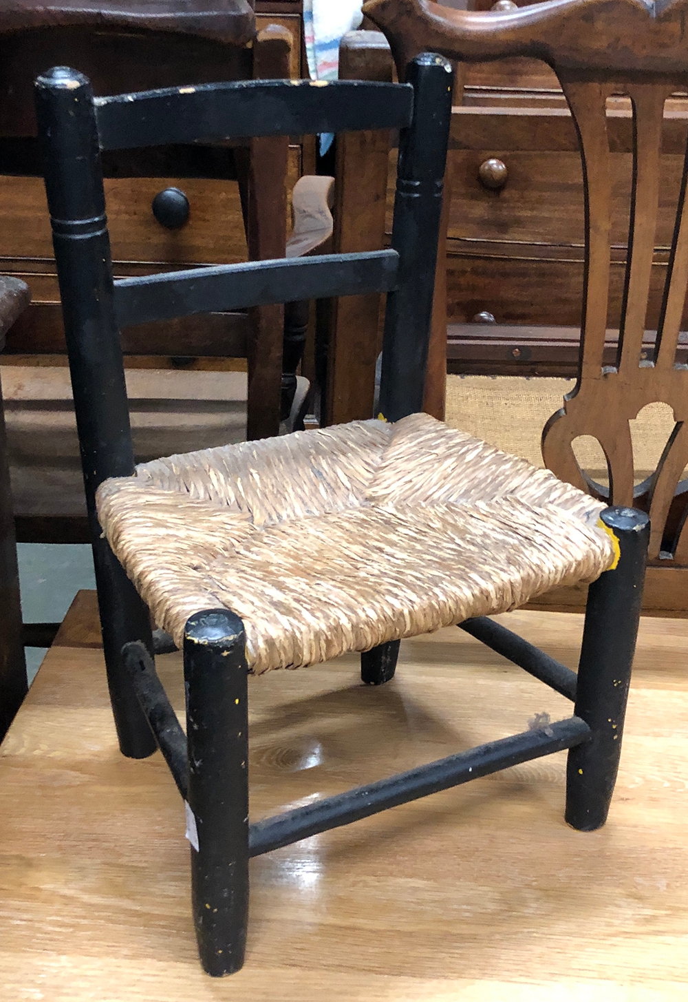 An ebonised child's/dolls chair with rush seat, height of seat 22cmH
