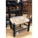 An ebonised child's/dolls chair with rush seat, height of seat 22cmH