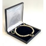 A cased costume faux pearl necklace and earring set, each with white stones and a central faceted