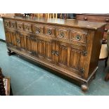 A 20th century large oak sideboard, having four drawers over four linenfold cupboard doors, on bun