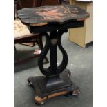 A 19th century black japanned sewing table (af), shaped top on a lyre support, with ormolu mask