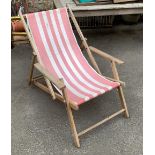 A folding deck chair, with arms, in a pink striped fabric