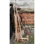 A mixed lot of long handled garden tools to include spades, rakes, saws, etc