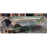 A galvanised wheelbarrow, with a selection of garden tools