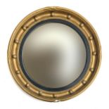 A 20th century regency style convex circular mirror with ebonised reeded slip and bobble moulding,