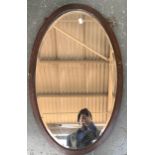 An oak framed oval wall mirror with bevelled glass, 81x51cm