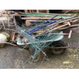 A mixed lot of garden tools and flower supports, with a plastic wheelbarrow