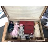 A vintage suitcase containing a quantity of dolls, composite and china, together with a vintage