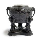 A Japanese Meiji era bronze censer, decorated with flora and fauna, supported on the shoulders of