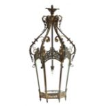 A wrought metal scrolling hanging lantern, of tapered hexagonal form, with six bevelled glass