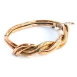 A 9ct gold bangle, entwined design with safety chain, approx. 11.1g