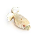 A 19th century Japanese mother of pearl netsuke in the form of a fish, set with coral eye, 4cm long