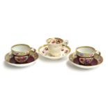 A pair of Meissen teacups and saucers, burgundy ground with floral panel decoration, the rims with a