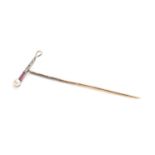 A yellow metal stick pin mounted with a hunting whip set with rubies, diamonds and a pearl, 1.9g,