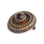 A 15ct gold Victorian Etruscan Revival brooch, set with central garnet cabochon, locket to