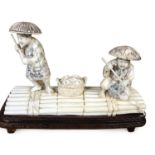 A Japanese ivory okimono of two fishermen on a raft, with basket of fish between them, signed to