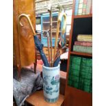 A Chinese stick stand decorated with images of flowers and birds, containing a shooting stick,