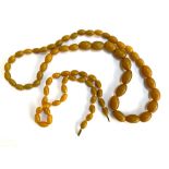 Two string of amber coloured beads, the larger with no clasp 33cmL, the smaller 46cmL
