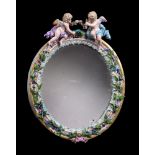 A Meissen flower encrusted and gilt metal mounted oval strut looking glass, surmounted with putti,