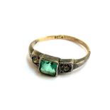 A 9ct gold and silver ring set with a central princess cut emerald paste flanked by smaller white