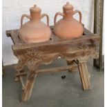 A pair of 20th century terracotta oil jars, in a trestle style stand with carved floral motif,