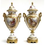 A pair of 20th century decorative porcelain ormolu mounted urns, each with a panel depicting