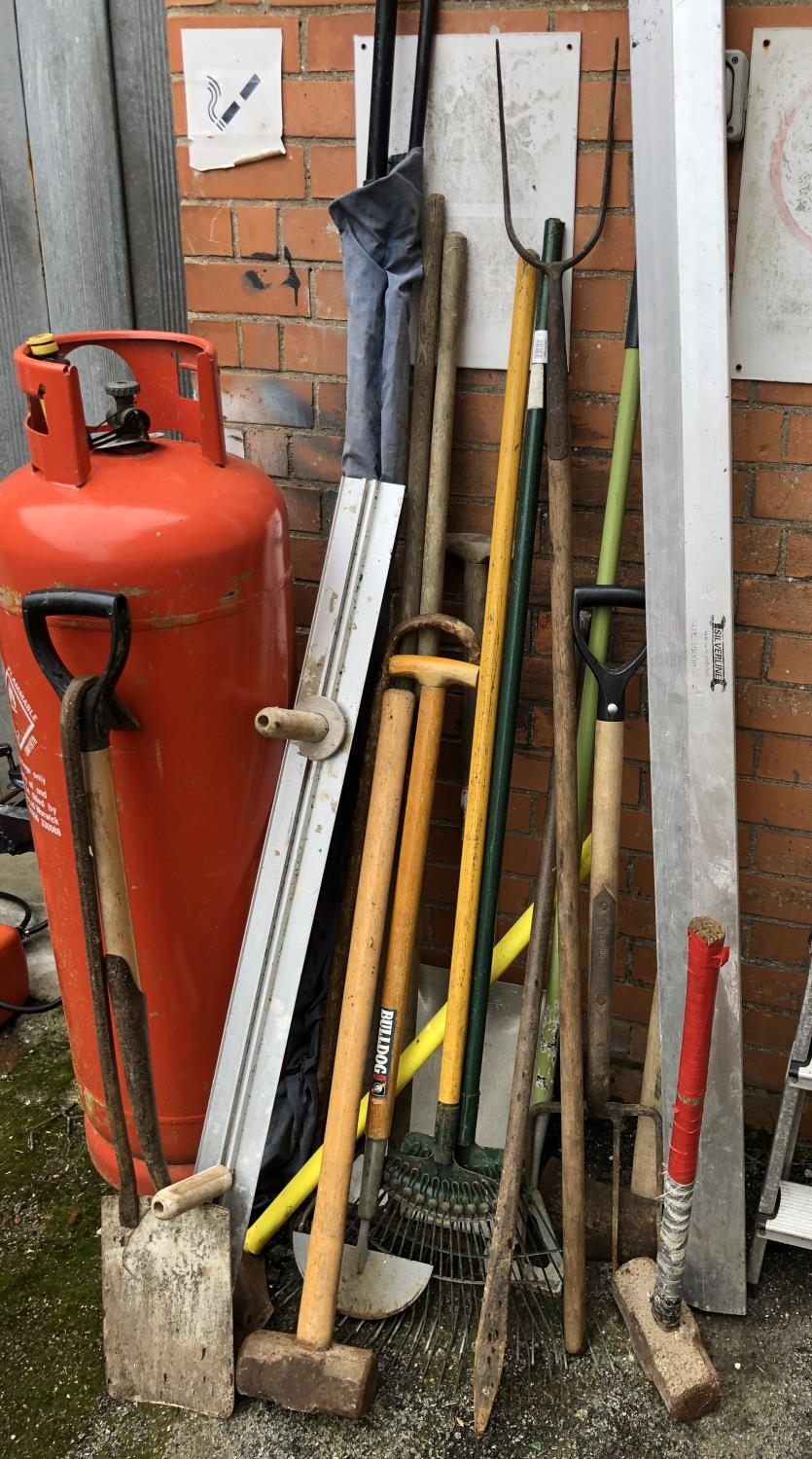 A quantity of garden tools to include sledgehammer, spades, rakes, axe, etc