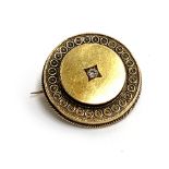 A gold brooch set with a single central diamond, tests as 14ct or higher, locket compartment to