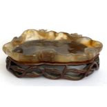 A Chinese carved agate brush washer in the form of a lily pad, on a pierced hardwood base, 15cmW,