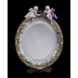 A Meissen flower encrusted and gilt metal mounted oval strut looking glass, surmounted with putti,
