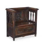 A carved oak hall seat in antiquarian taste last quarter 19th century with galleried arms and