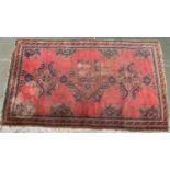 A slightly worn red ground wool rug, 205x125cm