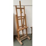 A very large beechwood artists studio easel; together with a further portable easel