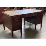 A 20th century kneehole desk, with the traditional arrangement of seven drawers, bears label for