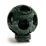 A Chinese 'jade' puzzle ball with small plinth stand, 9cmD