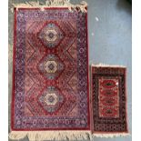 A small Persian silk rug, 117x70cm; together with one other miniature rug, 61x33cm (2)