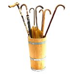 A coopered stick stand, containing several walking sticks, an umbrella with silver collar, etc