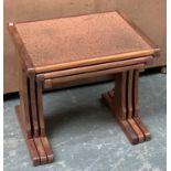 A nest of three teak tables with hammered copper effect tops; together with a pot stand with