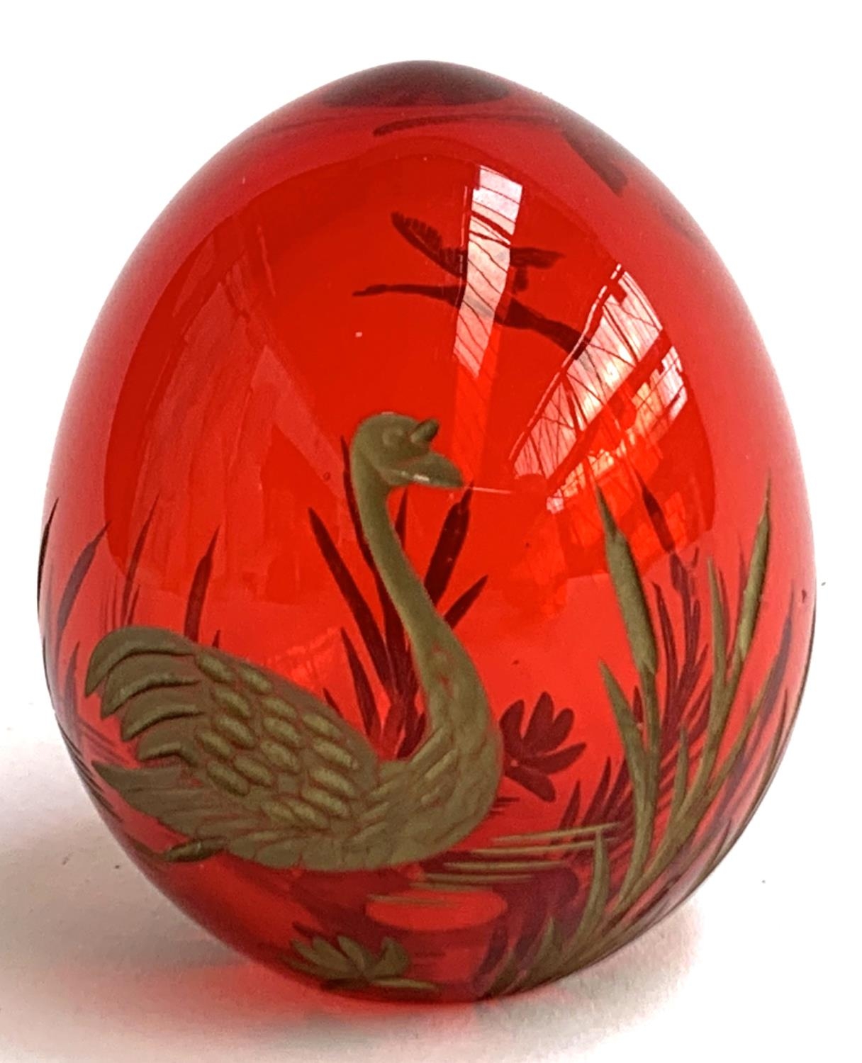 A Russian Faberge style cranberry glass egg, with engraved gilt decoration of swans and rushes, 6cmH