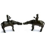 A pair of bronze sculptures of figures riding water buffalo, both AF, 24cmH