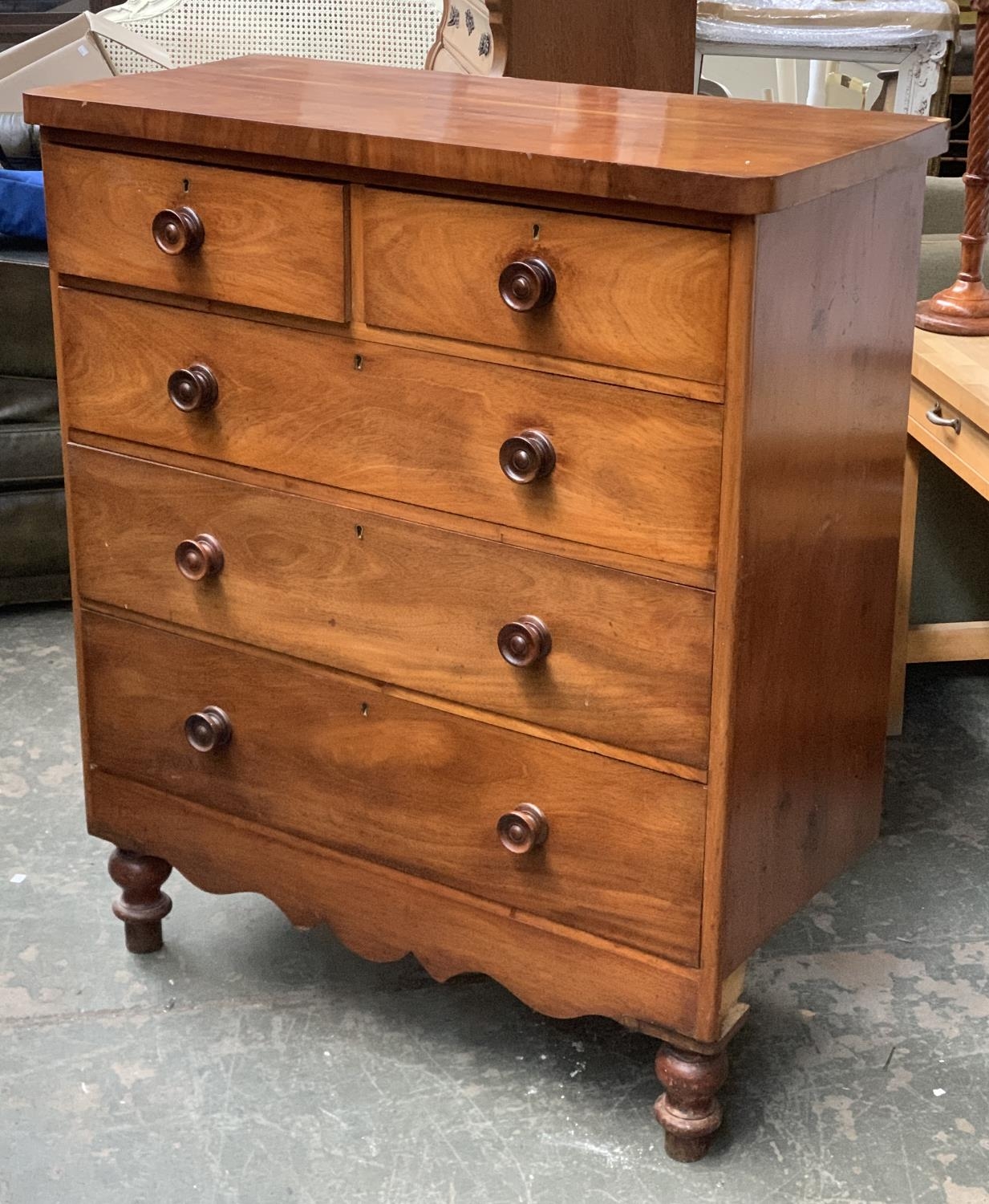 A Victorian mahogany chest of two short over three long drawers, on a shaped apron and turned