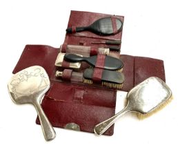 A morocco leather vanity set, with ebonised brushes and looking glass and white metal topped