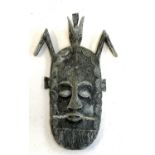 A decorative cast metal tribal mask, 34cmL