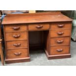 A Victorian mahogany kneehole desk, moulded top over an arrangement of nine drawers on a plinth