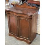 A Victorian and later rosewood chiffonier, carved upstand, serpentine top, two panelled doors, on